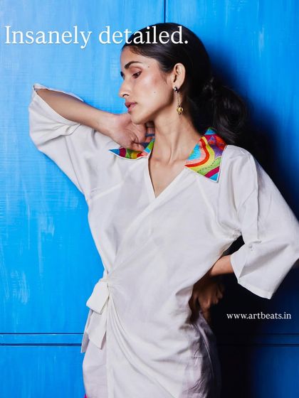 Insanely detailed. The collar on this white wrap top is a work of art in itself, with colorful, hand-embroidered patterns that make it one of a kind.