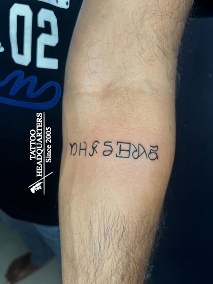 A custom script tattoo on the forearm, showcasing a unique and personalized font style.