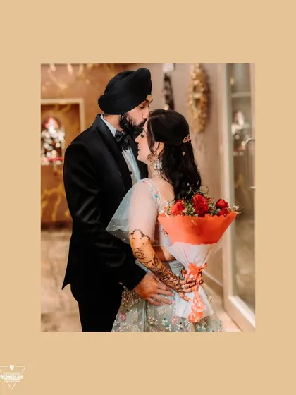 A sweet and romantic portrait of the couple, the groom embracing the bride as she holds a bouquet of red roses.