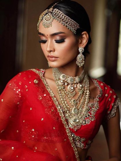 A softer, more romantic portrait of the bride in red. The makeup looks flawless even with her eyes closed, showcasing the seamless blending.