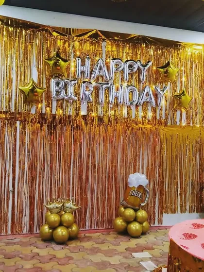 A fun and unique birthday theme for an adult party. This setup features a golden shimmer curtain and balloon pillars designed to look like beer and whiskey bottles.