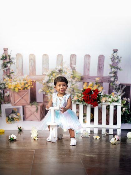 Taking a ride through her first year! This little birthday girl poses with a cute white tricycle in our rustic floral garden setup, adding a touch of playful charm to her milestone photos.