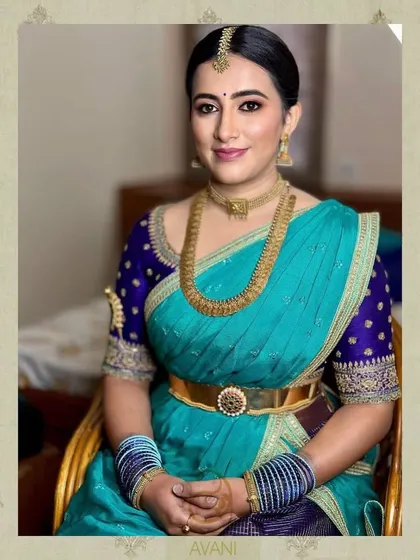 A beautiful turquoise Kanchipuram saree paired with a contrasting royal blue blouse. The blouse features intricate gold embroidery that picks up the gold threads in the saree.