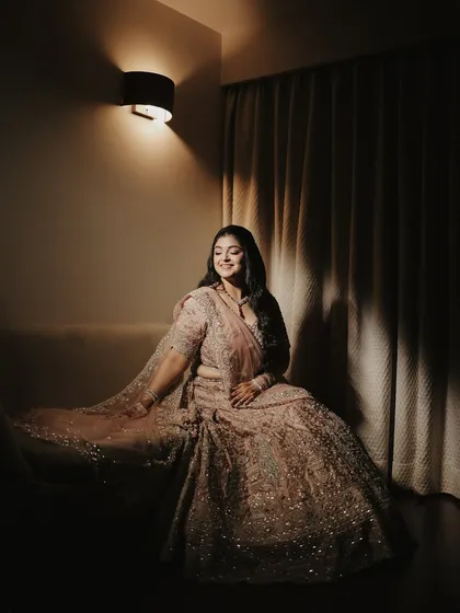 A moody and elegant portrait of the bride in her Roka lehenga. The dramatic lighting creates beautiful shadows, highlighting the texture of her outfit and her serene expression.