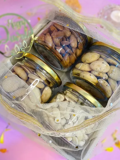 A close-up of the tray hamper for Diwali, filled with jars of almonds, cashews, and chilli cheese cookies.