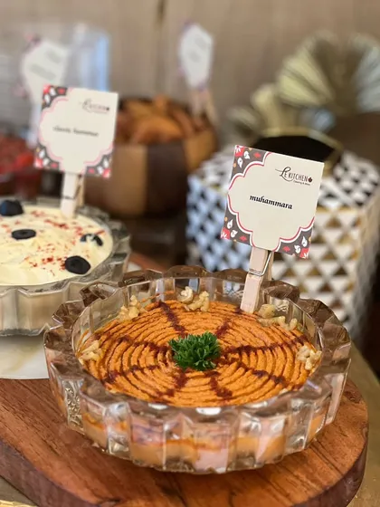 A display of my house-made dips, featuring a classic hummus and a vibrant muhammara. I serve these with a variety of breads and chips for a perfect grazing station.