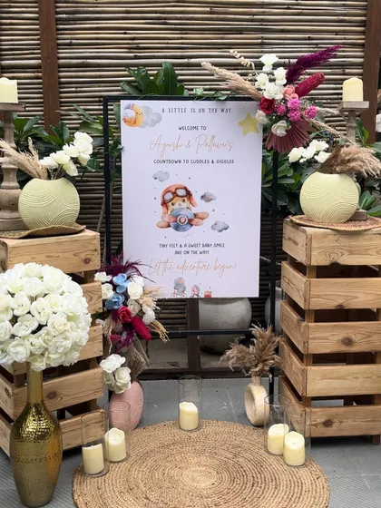 The welcome area for the "Miniature Miracle" baby shower. A personalized sign is surrounded by rustic wooden crates, candles, and beautiful boho floral arrangements, creating a warm and inviting entrance.