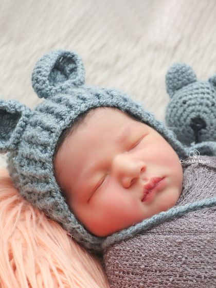 The texture of the knitted bear hat perfectly complements the softness of this baby's skin. This close-up captures the essence of a cozy, sleepy newborn.