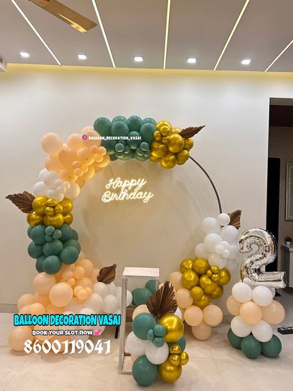 A stylish and modern balloon decoration for a 2nd birthday. The pastel peach and green balloons are accented with dried palm leaves for a boho touch.