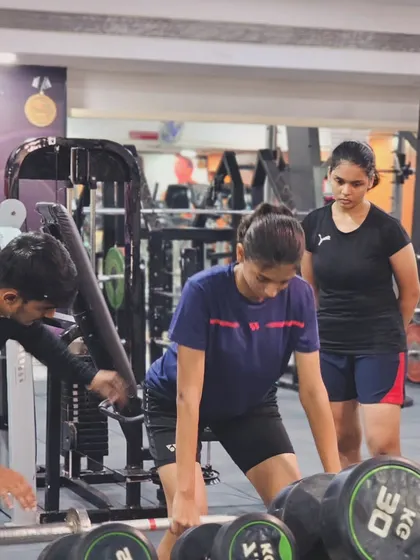 Under the watchful eye of a coach, a player works on her deadlift form, building core and leg strength for a solid on-court base.