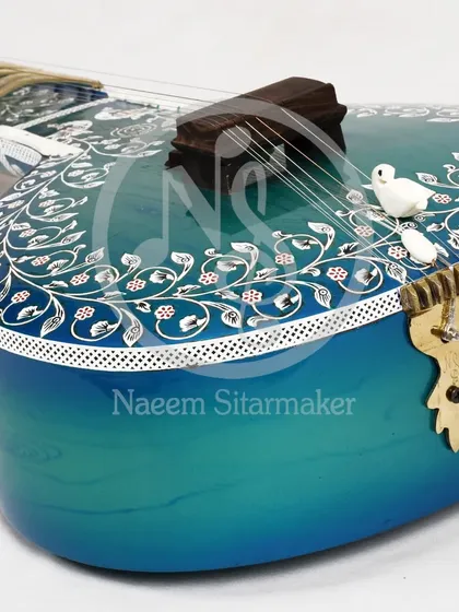 A close up of the side of the blue rock sitar, highlighting the small, hand-carved birds on the bridge and the detailed border inlay.