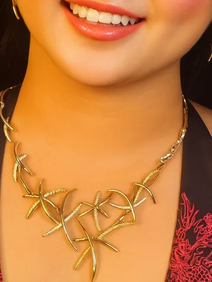 A unique, modern gold-toned necklace with a starfish-like design. This is a statement piece perfect for a cocktail party or a beach wedding.