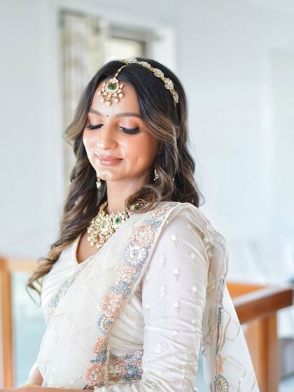 A serene portrait of the model in the white lehenga, highlighting the beautiful sheesh patti and matching necklace.
