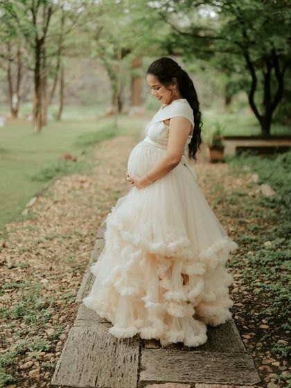 A serene moment in our ivory ruffled maternity gown. The multi-layered skirt adds texture and volume, creating a soft and romantic silhouette for your pregnancy photoshoot.