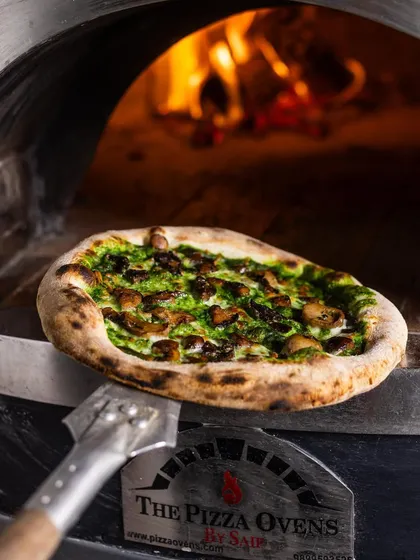 Our Mushroom pizza with a spinach cream base, fresh from the oven. The aroma of truffle oil and baked mushrooms is irresistible.