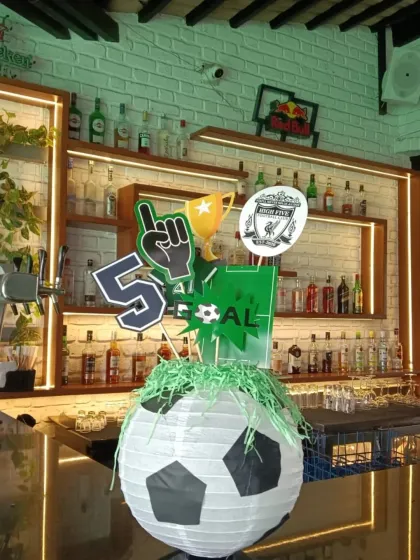 Even the bar area gets a sporty makeover with this custom centerpiece featuring a soccer ball lantern and themed cutouts.