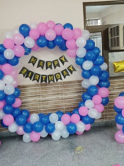 A simple and sweet 7th birthday decoration at home. This balloon ring in blue, pink, and white is a great backdrop for photos, complete with a balloon pillar holding the number '7' foil balloon.