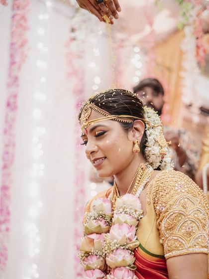 A close-up of the bride during the 'akshata' ceremony, with rice grains in her hair. This shot beautifully captures the blessings and traditions of a South Indian wedding.