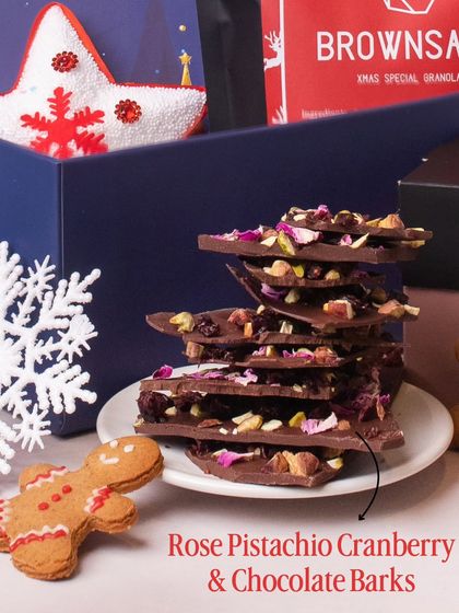 Our Rose Pistachio Cranberry & Chocolate Barks are a holiday favorite. Stacked beautifully on a plate, this image shows the rich texture and colorful ingredients that make this treat both delicious and visually appealing for any Christmas gift.