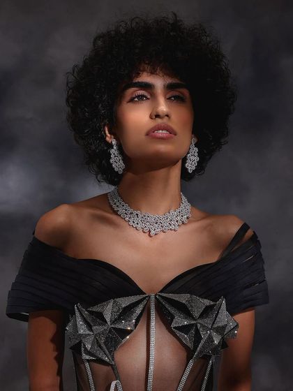 A powerful upward-looking shot for Purab Paschim, highlighting the sparkle of the diamond necklace against a moody, painted backdrop.