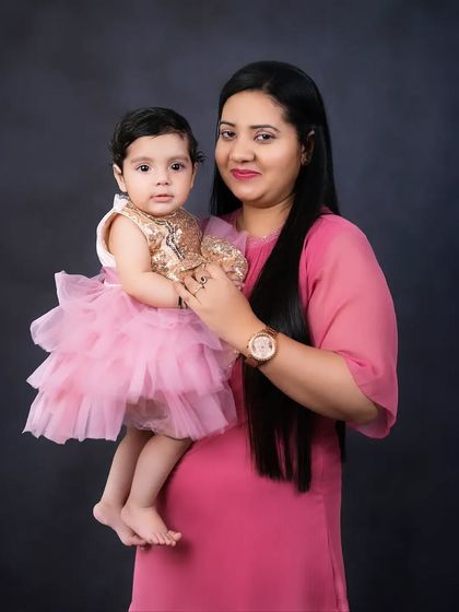 A mother holds her daughter, who is dressed in an adorable party dress. A beautiful and classic mother-daughter fine-art portrait.