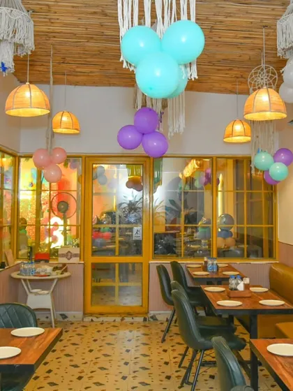 A view of our indoor dining room with its bohemian-style macrame and wicker light fixtures, decorated with party balloons.