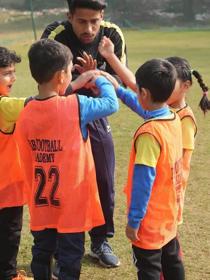 A coach and players in a huddle. We recognize the vital role coaches play in shaping the future of young athletes.