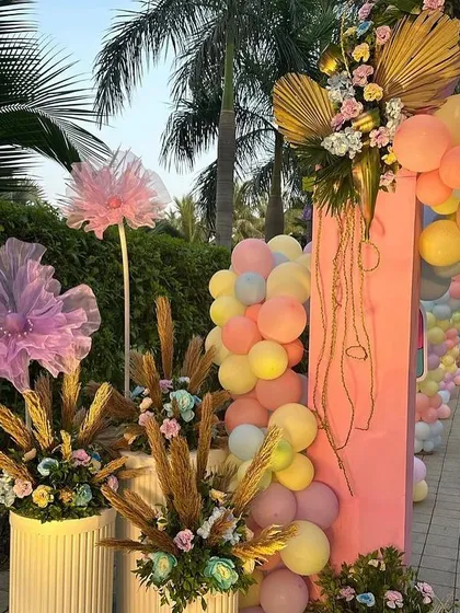 A close-up of the 'Candy Land' entrance arch, showing the mix of pastel balloons, dried palm leaves, and floral arrangements.