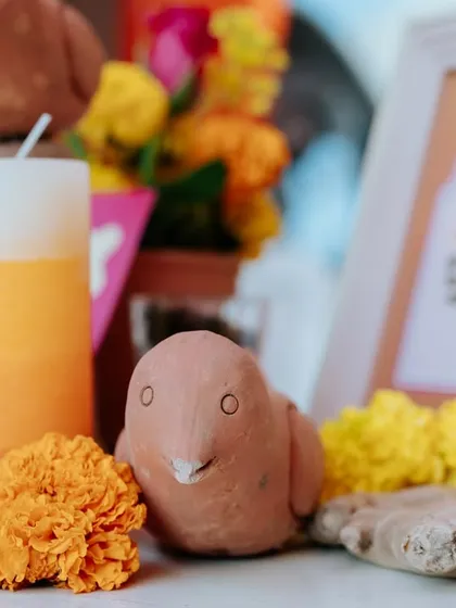 A close-up of a handcrafted clay bird, placed among fresh marigold flowers. These small, artisanal touches made the decor feel authentic and full of charm.