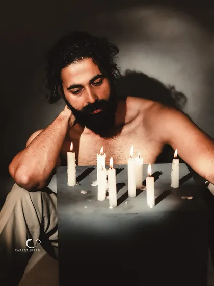 A moment of quiet contemplation. The soft light from the candles illuminates his face, creating a pensive and atmospheric portrait.