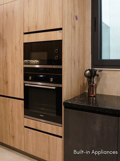 The built-in appliance unit in Esha Bahl's kitchen features a wood-look laminate that adds warmth and texture, beautifully contrasting with the darker cabinets.