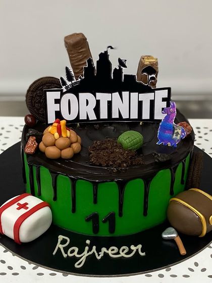 An epic Fortnite-themed cake for Rajveer's 11th birthday. It's loaded with edible game elements like a treasure chest, med kit, and the iconic llama.