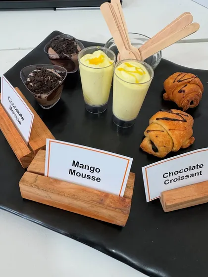 A dessert platter featuring our seasonal Mango Mousse, rich Chocolate Mousse, and flaky Chocolate Croissants. We offer a variety of modern desserts to complement our traditional Indian sweets.