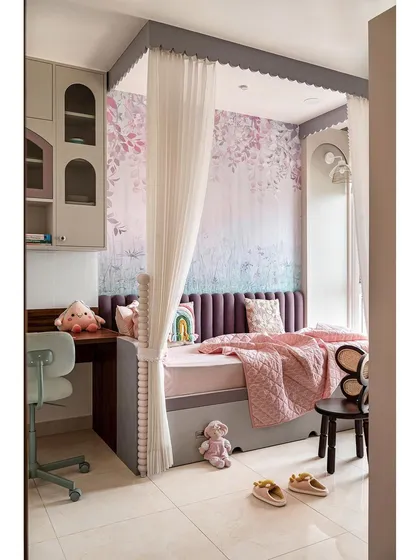This kids' bedroom is full of playful pastel hues and clever solutions. A single bed with a pullout for playdates is enclosed by sheer curtains with scallop details, creating a cozy canopy.