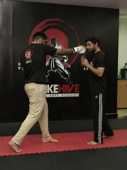 A coach demonstrates the proper form for a straight punch. This one-on-one instruction is key to our teaching philosophy, ensuring every student learns correctly from the start.