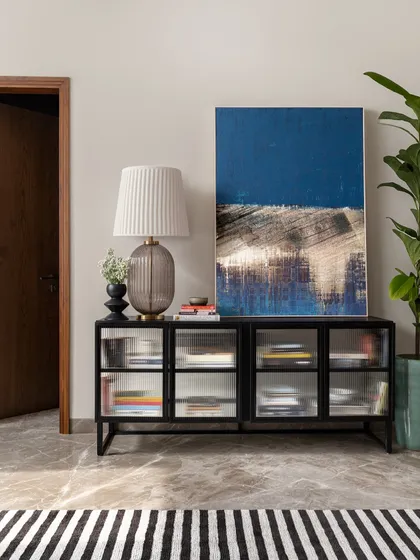A carefully composed vignette featuring a fluted glass console, abstract art, and a sculptural lamp. These finishing touches are what bring a room to life and give it a unique personality.