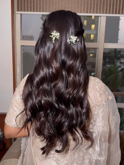 The final look from the back: a simple half-up twist with soft waves, adorned with delicate baby's breath.
