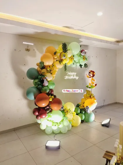 A circular balloon arch with a jungle theme, set up against a plain wall. This shows how I can create a big impact in a simple space.