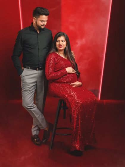 A classic seated portrait of the mom-to-be with her partner standing by her side, exuding confidence and joy.