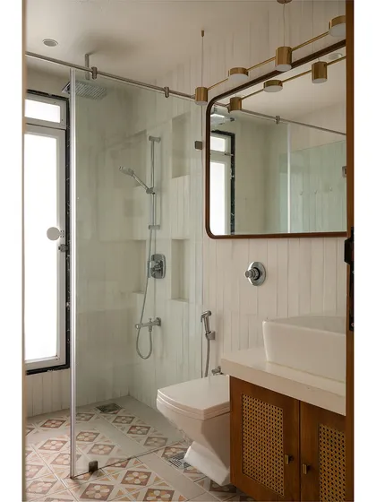 Another bathroom from the "Apartment 222" revamp. The combination of patterned floor tiles, simple white wall tiles, and a wood and cane vanity creates a warm and inviting space that feels both timeless and modern.
