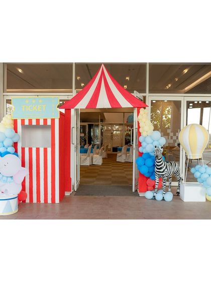 A welcoming entrance to a circus party, featuring a classic ticket booth, a friendly elephant prop, and a zebra, all ready to greet the guests.