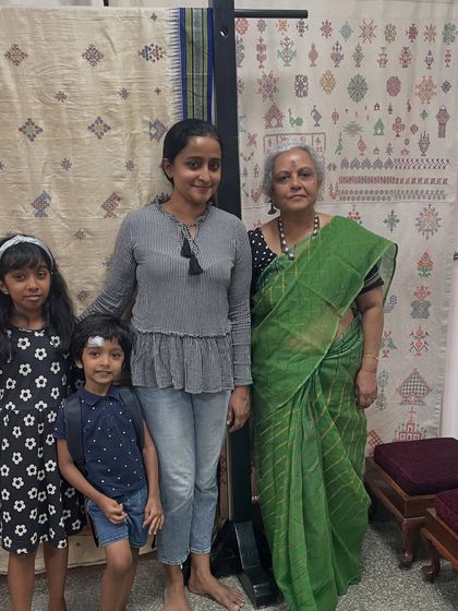 A family poses in front of a large Kasuti tapestry during a workshop. It's lovely to see inquisitive kids tagging along with their mothers to learn.