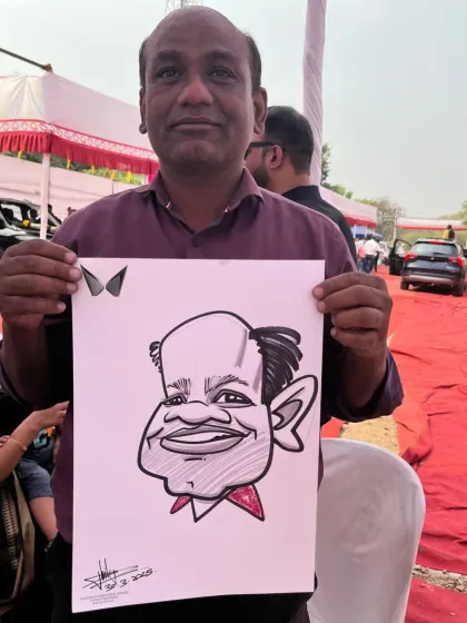 An older gentleman proudly holding his caricature at the same outdoor event.