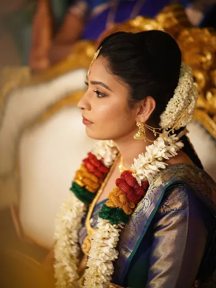 A side profile of the bride, showing her traditional hairstyle and jewelry. The makeup is applied to look beautiful from all angles.