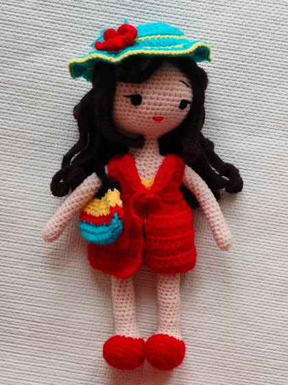 This doll is ready for a holiday with her hat and colorful bag. Her dress, shoes, and accessories are all removable.