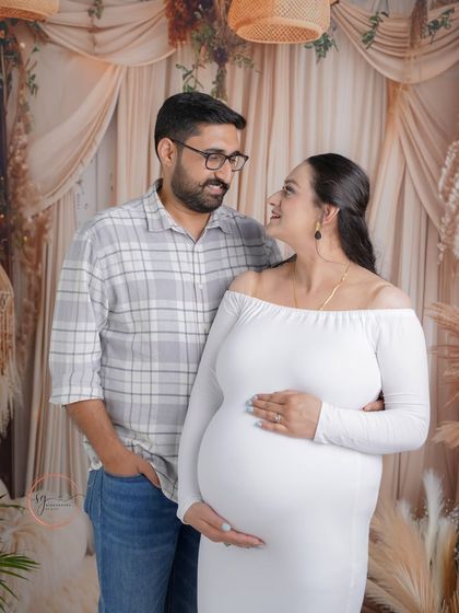 Sharing a loving gaze in our warm, boho-themed studio setup. This couple's maternity portrait is all about capturing the natural and relaxed connection between them.