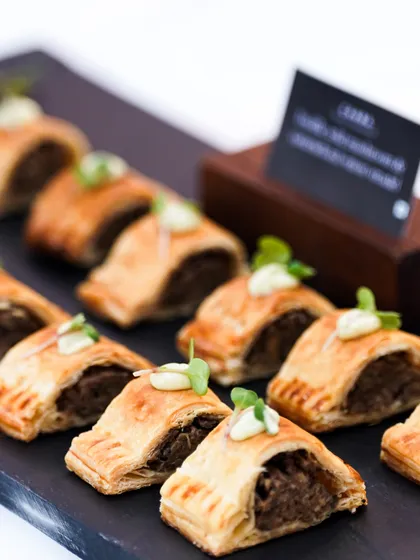 Our savory lamb and mint sausage rolls, a classic canapé for events like the Cavalry Polo Match. These flaky pastries are filled with seasoned lamb and are always a crowd-pleaser.