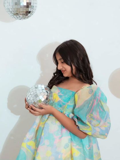 A close-up of the birthday girl holding a disco ball, with a dreamy, colorful dress that perfectly matches the fun vibe of the shoot.
