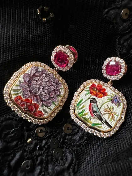 A playful, asymmetrical pair featuring a bird on one side and a purple aster flower on the other. The vibrant colours are created with tiny, hand-set mosaic pieces and framed with rubies and diamonds.