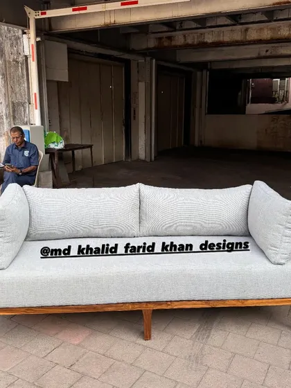A custom sofa with cane paneling on the arms, upholstered in a light grey fabric.